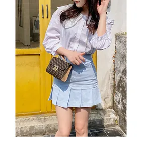 Outdoor model shot showing white lace collar blouse and blue pleated mini skirt
