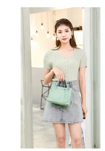Detail of light green handbag featuring embossed cartoon patterns and dual top handles