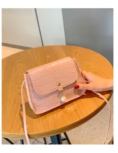Detailed view of pink croc-embossed small square bag with pearl charm and metal buckle