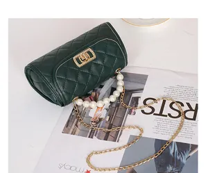 Détail du sac cylindre matelassé vert foncé avec poignée en perles et fermoir rotatif doré