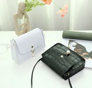 Detail of crocodile embossed mini square bags with pearl charms in black and white