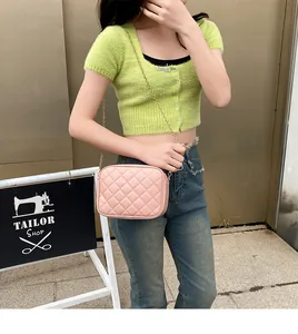 Pink quilted chain crossbody bag shown with green sweater and denim pants