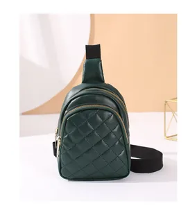 Detailed macro view of dark green quilted crossbody bag with dual golden zippers