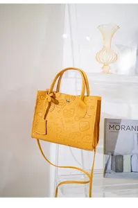 Detail of yellow embossed faux leather handbag showing intricate floral patterns and textures