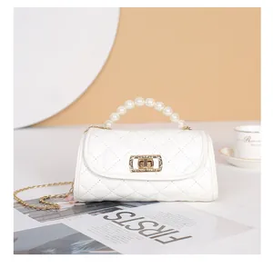 Détail d'un sac cylindre blanc matelassé avec poignée en perles et fermoir doré