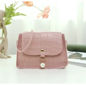 Detailed view of pink croc-embossed small square bag with white pearl charm ornament