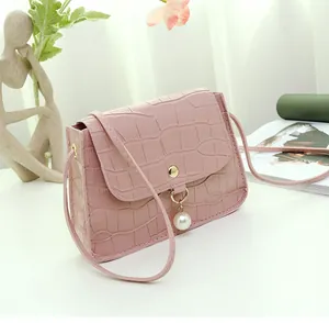 Detail of pink faux crocodile leather bag with gold buckle and pearl drop accessory