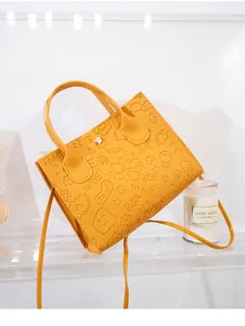 Detailed macro view of yellow embossed crossbody bag with 3D patterns and pearl decoration
