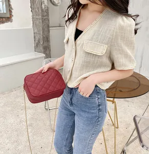 Detail of red quilted chain crossbody bag with cream tweed jacket in street style