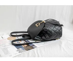 Dettaglio mini zaino nero trapuntato con ciondolo gatto di perle su rivista di moda