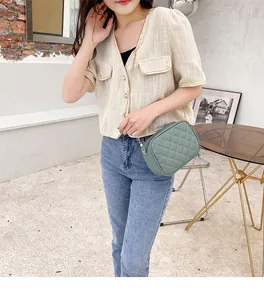 Sage green quilted camera bag with gold chain strap worn by a model in a cafe setting