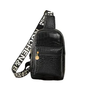 Black crocodile embossed crossbody chest bag with decorative black and white woven strap