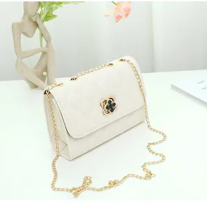 Detail of white quilted handbag with golden chain strap and floral metal clasp closure