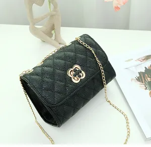 Detail of black quilted leather texture and gold flower clasp on shoulder bag
