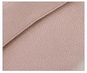 Nahaufnahme der rosa Ledertextur mit Litschi-Muster und feiner Naht an der Tasche
