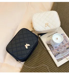 Detail of rhombus quilted bags with butterfly buckles and gold chain straps