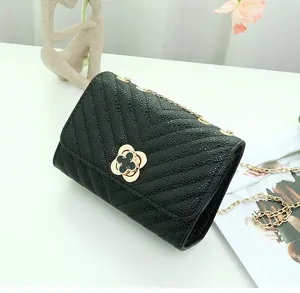 Detail of V-quilted black chain bag with a gold clover clasp and textured finish