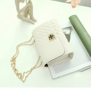 Detail of cream V-quilted faux leather bag featuring a gold clover twist lock and chain