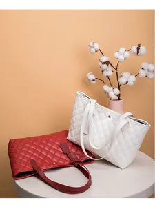 Détail macro du motif matelassé en losange sur les grands cabas en cuir rouge et blanc