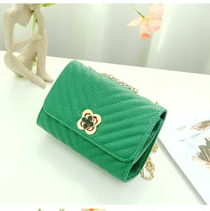 Detail of green quilted leather bag with V-shaped stitching and gold clover clasp