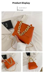 Detailansicht der orangen Lederhandtasche mit klobigem Goldketten-Griff und Riemen