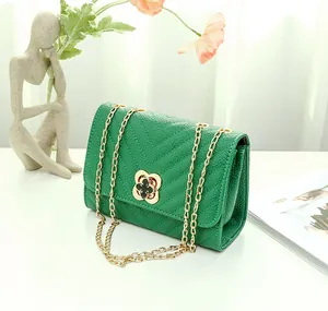 Detail of emerald green crossbody bag with V-quilted texture and gold clover clasp