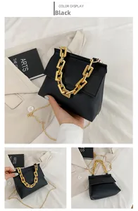 Detail der schwarzen Tasche mit grobem goldenem Kettengriff und schmalem Schulterriemen