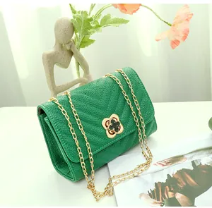 Detail view of emerald green crossbody bag with V-quilt pattern and gold floral clasp