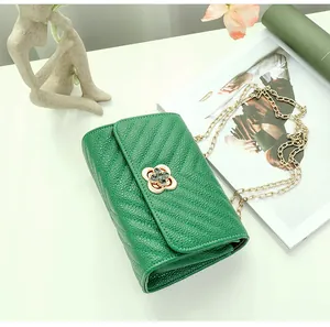 Close-up of green quilted leather bag with golden flower clasp and chain strap