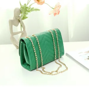 Close-up of emerald green V-quilted faux leather bag with elegant gold chain strap