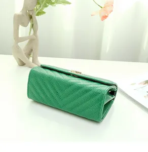 Close-up of green V-quilted faux leather bag with elegant golden rotary lock on a white desk