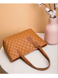 Détail du sac cabas matelassé marron avec fermoir magnétique doré et pendentif en cuir