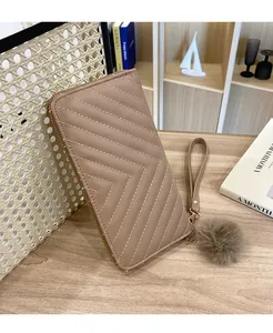 Detailed shot of long taupe V-quilted wallet with wristlet strap and fluffy fur ball charm