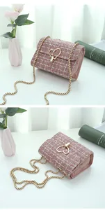 Detail of pink plaid woven crossbody bag featuring a golden heart lock and chain strap
