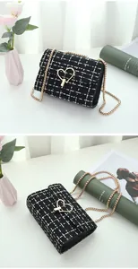 Detail of tweed crossbody bag featuring a golden heart lock and woven chain strap