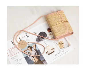 Close-up of woven straw handbag with gold tassel detail and pink leather shoulder strap
