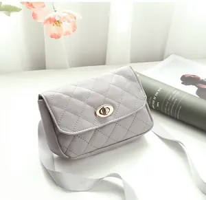 Détail du motif matelassé avec un fermoir rotatif en métal doré sur un sac gris clair