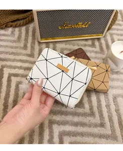 Dettaglio di piccoli portafogli con motivi geometrici in bianco, beige e marrone con zip