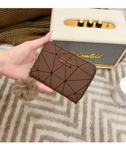 Dettaglio di un portafoglio marrone in pelle sintetica con motivi geometrici e pompon