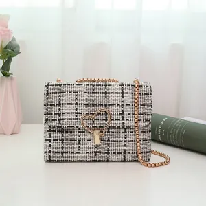 Black and white tweed crossbody bag with heart-shaped gold lock and chain strap