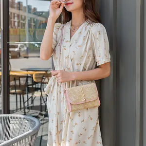 Straw woven flap crossbody bag with pink leather trim and elegant golden metal bar clasp