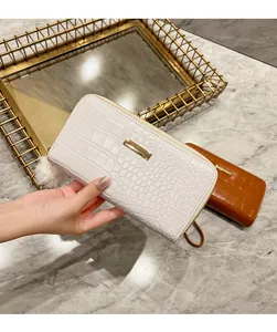 Detail of white crocodile pattern long wallet featuring metal bar and furry ball charm