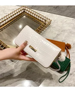 Close-up of crocodile pattern long wallet with gold hardware and plush ball charm