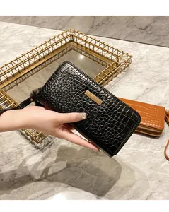Detail of black faux crocodile leather wallet with gold metal bar and wristlet strap