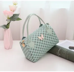 Detail of mint green monogram boston bag with pink butterfly charm and gold hardware