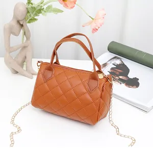Detail of a brown quilted barrel bag featuring gold zippers and an elegant chain strap