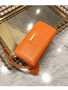 Close-up of orange crocodile pattern long wallet with gold plate and pompom charm