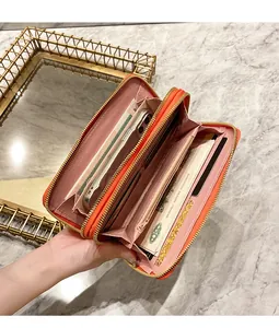 Detail view of orange long double-zipper wallet interior holding smartphone and cash
