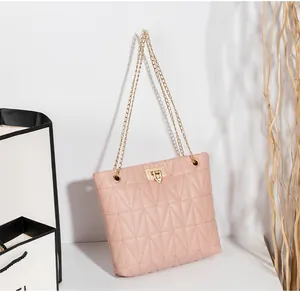 Detail of pink quilted tote bag featuring a gold rectangle twist lock and chain strap