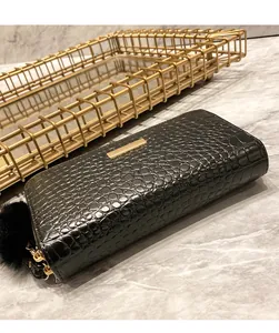 Detail of black crocodile texture wallet with gold metal plate and plush ball charm